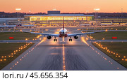 Passenger airplane landing on runway at dusk with airport terminal in background. Стоковое AI-изображение, AI-художник Юрий Поздников / Фотобанк Лори