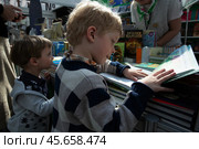 Международная ярмарка интеллектуальной литературы «non/fictioNвесна» в Гостином дворе. Маленький мальчик смотрит книгу. (2023 год). Редакционное фото, фотограф Дмитрий Киселёв / Фотобанк Лори