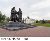 Памятник князю Александру Невскому с семьей  в центре Белорусского города Витебск, символизирующий историческую связь времен,  духовное единство и семейные ценности. Скульптура выполнена из черного камня и окружена зелеными насаждениями. Вдалеке виднеется старинная белокаменная Благовещенская церковь и часовня с колоколами. По зеленому осеннему скверу гуляют горожане и туристы. Редакционное фото, фотограф Сергей Никифоров-Гордеев / Фотобанк Лори