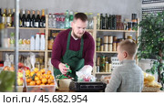 Seller weighs candies in a bag for a boy. Child buys sweets in a supermarket. Стоковое видео, видеограф Яков Филимонов / Фотобанк Лори