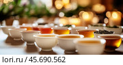 Tea ceremony showing different teas and infusions with candles in the background. Стоковое AI-изображение, AI-художник Юрий Поздников / Фотобанк Лори