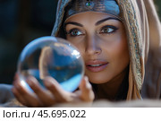 Gypsy fortune teller peers into a glass ball. Стоковое AI-изображение, AI-художник Евгений Харитонов / Фотобанк Лори