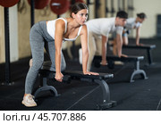 Athletic young woman pumping her biceps with a dumbbell while leaning on bench. Стоковое фото, фотограф Яков Филимонов / Фотобанк Лори
