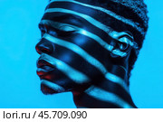 Portrait of a young guy with blue light patterns accentuating his facial features. Стоковое AI-изображение, AI-художник Ярославский Максим / Фотобанк Лори