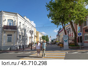 Город Витебск, Беларусь. Вид на пешеходную улицу Суворова летним солнечным днем. Две девушки идут по пешеходному переходу спиной к зрителю. Вдалеке видна Воскресенcкая (Рынковая) церковь (2024 год). Редакционное фото, фотограф Наталья Николаева / Фотобанк Лори