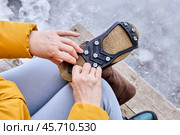 Rubber lining with spikes is stretched onto sole of winter boot to improve traction and prevent slipping. Стоковое фото, фотограф Владимир Григорьев / Фотобанк Лори