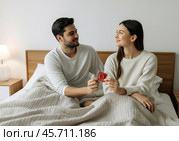 Пара в постели держит блистер презерватива. Стоковое AI-изображение, AI-художник Anna Leeva / Фотобанк Лори