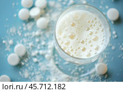 Glass of effervescent soluble vitamin pills on blue background. Стоковое AI-изображение, AI-художник Иван Рябоконь / Фотобанк Лори