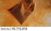 Close up of tea bag diffusing in a clear glass. Macro slow motion shot of the process of brewing herbal. Стоковое видео, видеограф Андрей Армягов / Фотобанк Лори