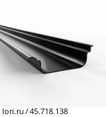 Black plastic rain gutter lying on white background. Стоковое AI-изображение, AI-художник Иван Рябоконь / Фотобанк Лори