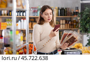 In trading floor of minimarket, girl buyer inspects hamon, scan QR code on product label. Стоковое фото, фотограф Яков Филимонов / Фотобанк Лори