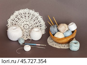 Close-up of wooden bowl with skeins of light natural cotton yarn for crocheting, crochet hooks and handmade lace round doilies on brown background. Crochet as a hobby. DIY concept. Beautiful still life. Стоковое фото, фотограф Виктория Катьянова / Фотобанк Лори
