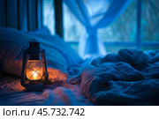 Vintage lantern casting warm light on unmade bed in a bedroom at night. Стоковое AI-изображение, AI-художник Иван Рябоконь / Фотобанк Лори