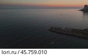 Serene sea mirroring sunset hues, small boat nearing mersin coastline, silhouetted figures standing on weathered wooden pier during twilight. Стоковое видео, видеограф ILIA GOROKHOV / Фотобанк Лори