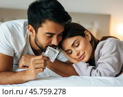Пара лёжа в постели держит блистер презерватива. Стоковое AI-изображение, AI-художник Anna Leeva / Фотобанк Лори