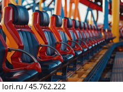 Empty rollercoaster seats waiting for passengers in amusement park. Стоковое AI-изображение, AI-художник Иван Рябоконь / Фотобанк Лори