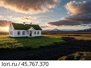 Landscape of Icelandic countryside with typical view of turf-top white house at sunset sky. Scenery of dramatic summer sunrise in Iceland or Norway, traveling. Severe north concept. Copy ad text space. Стоковое AI-изображение, AI-художник Aleksandr Golubev / Фотобанк Лори