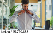 Elegant businessman buttoning shirt in modern office. Стоковое AI-видео, аниматор Юрий Поздников / Фотобанк Лори