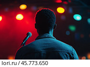 Performer stands near microphone under colorful lights at evening event. Стоковое AI-изображение, AI-художник Юлия Гапеенко / Фотобанк Лори