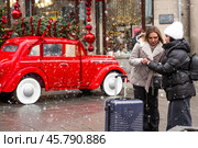 The new year is 2025. Tourists girls with a suitcase in the center of Moscow. Tourism in Russia for the New Year holidays. New Year decorations in Moscow. Christmas holidays. Russia, Moscow, December 2024. Редакционное фото, фотограф Photojuli / Фотобанк Лори