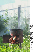 A lit fire with wood in the stove for cooking pilaf outside. Small iron stove with a chimney outside. Стоковое видео, видеограф Кашапова Эльвира / Фотобанк Лори