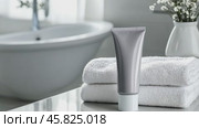 Blank cosmetic plastic gray tube mockup. Cream lotion gel packaging, white bathroom towel stack. Skincare beauty product. Marketing branding template mock up. Empty brand design background. Self care. Стоковое AI-видео, аниматор Марина Демидюк / Фотобанк Лори