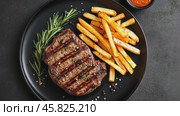 Steak and fries. Hot grilled steak with french fries on black plate on a dark slate stone background. Top view, flat lay. Steak and chips. Juicy roasted beefsteak tenderloin with crispy potatoes dish. Стоковое AI-видео, аниматор Марина Демидюк / Фотобанк Лори