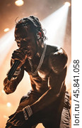 Travis scott performing live on stage, singing with passion and energy. Стоковое AI-изображение, AI-художник Юрий Поздников / Фотобанк Лори
