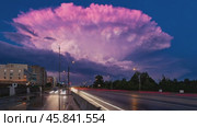 Pink cumulonimbus cloud looming over city highway at dusk. Стоковое AI-видео, аниматор Юрий Поздников / Фотобанк Лори