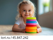 Веселый ребенок играет с яркой игрушкой, пирамидкой. Стоковое AI-изображение, AI-художник Щеголева Ольга / Фотобанк Лори