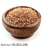 Wooden bowl overflowing with roasted buckwheat groats. Стоковое AI-изображение, AI-художник Иван Рябоконь / Фотобанк Лори
