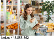 European teen girl customer at shop scans QR code on nougat package using phone camera. Стоковое фото, фотограф Яков Филимонов / Фотобанк Лори