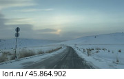 Video of winter snowy road on Tazheran steppe with snow-covered hills at sunset. Road to Baikal Lake coast. Scenic winter landscape. Natural background. Winter car traveling and outdoors. Стоковое видео, видеограф Виктория Катьянова / Фотобанк Лори