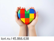 Child hands holding colorful heart puzzle, symbol of autism awareness and neurodiversity support. Стоковое AI-изображение, AI-художник Иван Рябоконь / Фотобанк Лори