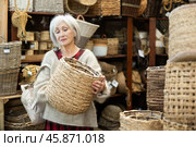 Female designer choosing decorative handmade wickerwork for interior in store. Стоковое фото, фотограф Яков Филимонов / Фотобанк Лори
