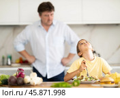 Father forcing little daughter to eat vegetable salad in kitchen. Стоковое фото, фотограф Татьяна Яцевич / Фотобанк Лори