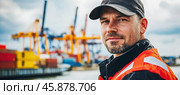 Port worker wearing high visibility vest supervising loading operations in a cargo port. Стоковое AI-изображение, AI-художник Юрий Поздников / Фотобанк Лори