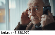 An elderly man is talking on a smartphone. The smartphone is in the hands of an elderly pensioner. A pensioner's conversation with scammers. Стоковое AI-изображение, AI-художник Терехова Марина / Фотобанк Лори
