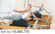 Cheerful man doing exercises on Pilates reformer with box. Стоковое фото, фотограф Яков Филимонов / Фотобанк Лори