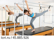 Woman working out on the trapeze table in fitness gym. Pilates and healthy lifestyle concept. Стоковое фото, фотограф Яков Филимонов / Фотобанк Лори