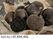 Freshly harvested black truffles showing intricate texture and cross section on rustic burlap. Стоковое AI-изображение, AI-художник Иван Рябоконь / Фотобанк Лори
