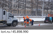 Город Кемерово. Работники АО "КемВод" меняют крышку колодца на городской улице. Редакционное фото, фотограф Цибаев Алексей / Фотобанк Лори