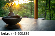Serene morning light on artisan soapstone counter with bowl and floral vase. Стоковое AI-изображение, AI-художник ФотоИнтеллект / Фотобанк Лори