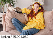Peaceful teen girl in modern headphones sit relax on comfortable couch listening to music. Стоковое фото, фотограф Гладских Татьяна / Фотобанк Лори