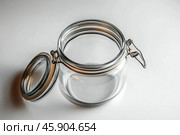 A glass jar with transparent walls and a hermetic lid. The lid is secured with a metal clamp with a rubber seal, ensuring a tight closure. The jar is open, and the lid lies on the side, which demonstrates the convenience of the mechanism. The simplicity and minimalism of the design emphasize its versatility and practicality. Стоковое AI-изображение, AI-художник Анна Кривицкая / Фотобанк Лори