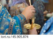 Priest in blue church vestment anoints with sacred oil from golden vessel. Стоковое фото, фотограф irisff / Фотобанк Лори