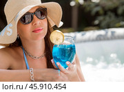 A young woman in a swimsuit and sunglasses in a Jacuzzi with a glass of Blue Lagoon cocktail on the background of the pool. The concept of a summer vacation, vacation and foam party. Стоковое фото, фотограф Photojuli / Фотобанк Лори