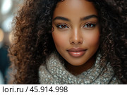 A young girl with an expressive appearance. Her face radiates warmth and natural beauty. She has large, brown eyes with long eyelashes, which emphasizes her soft, friendly look. Her hair is voluminous, dark brown, with natural curls, giving the image airiness and lightness. Thin, well-groomed eyebrows emphasize the harmony of her facial features. Her skin is radiant, with a light natural blush on her cheeks. Her lips are plump, covered with gloss, which gives them a moist and well-groomed look. She is dressed in a cozy scarf made of thick knitting in a gray-beige shade, which adds a sense of warmth and comfort to the image. The background is blurred, which focuses attention exclusively on the girl's face. Стоковое AI-изображение, AI-художник Анна Кривицкая / Фотобанк Лори
