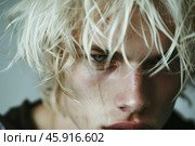Portrait of androgynous male model with messy platinum blond hair and blue eyes looking down. Стоковое AI-изображение, AI-художник Иван Рябоконь / Фотобанк Лори