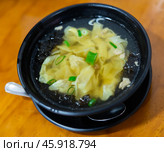 Wonton soup is cooked dumplings filled with meat or seafood. They are served in broth, usually enriched with onions and other ingredients. Chinese cuisine. Стоковое фото, фотограф Яков Филимонов / Фотобанк Лори